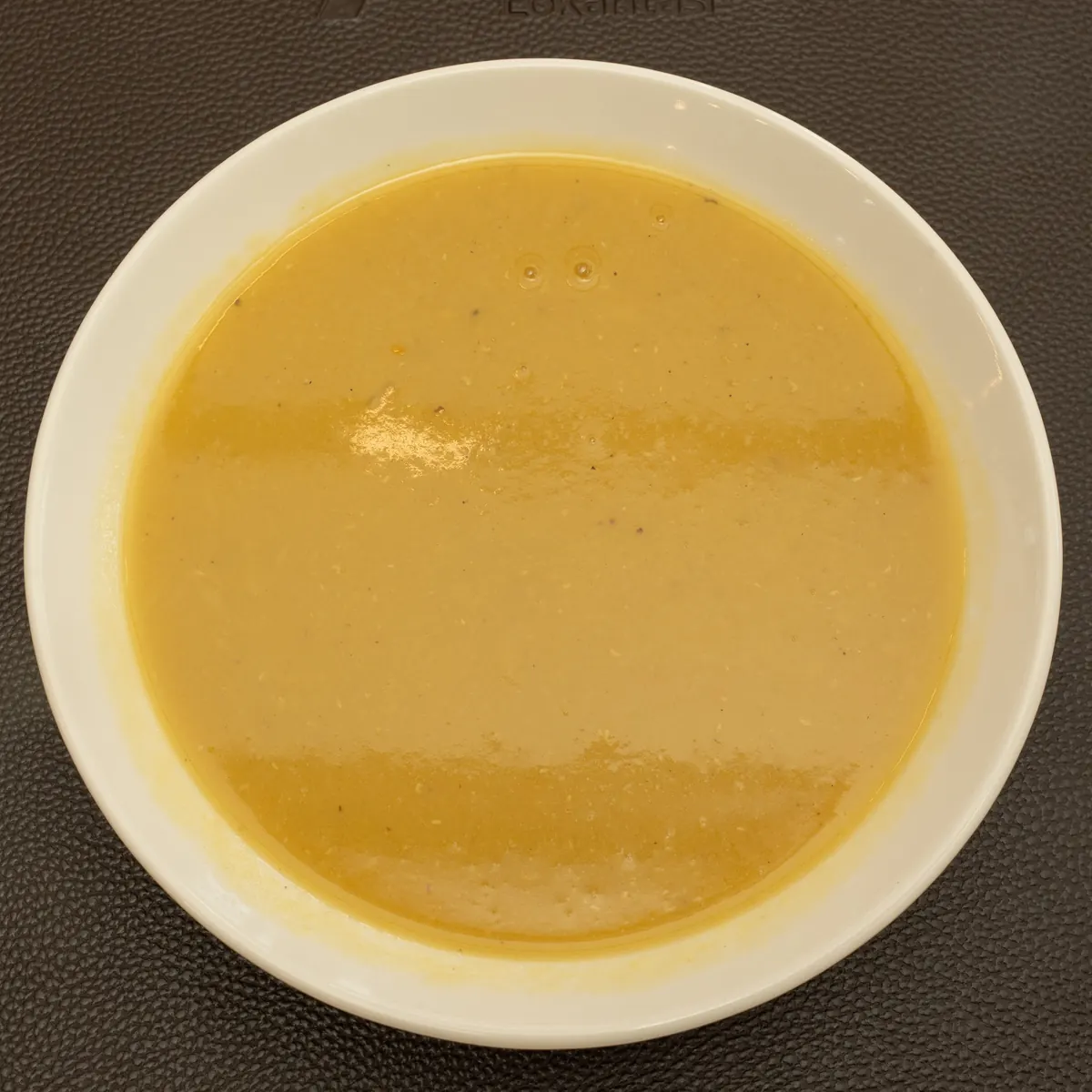 Beyaz çukur tabakta mercimek çorbası.